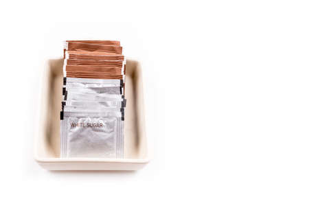 Row of white and brown sugar packs in a ceramic isolated on a white background. Copy space.
