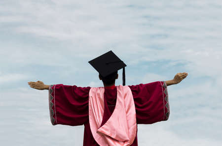 A student wearing robe of graduation. Concept of convocation. Sky background.の写真素材