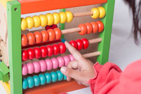 Kid learns on mathematic concept using colorful counting beads or abacus.