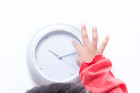 Kid's fingers pointing towards the digital clock. Top view.の写真素材