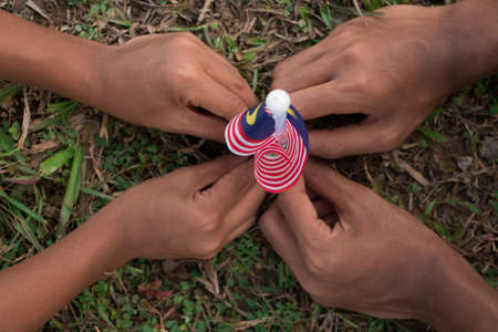 Independence Day concept - Kids' hands holding Malaysian flag on a field.