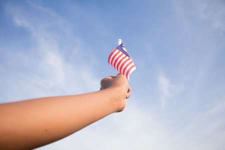 Independence Day concept. A happy and proud boy holding Malaysian flag. Sky background.