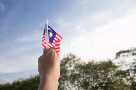 Independence Day concept. A happy and proud boy holding Malaysian flag. Sky background.の写真素材