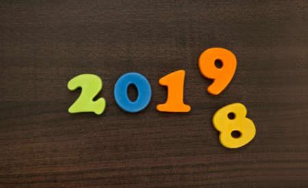Year 2019 with number 8 falling down. End of year. New year is coming. Wooden background.