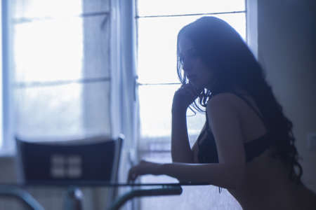 Portrait of sexy brunette sitting in the kitchen in his underwearの写真素材