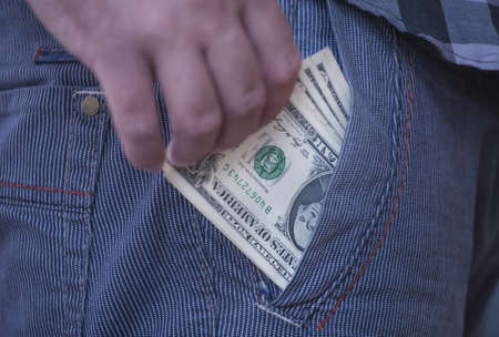 human hand is putting money in the pocket