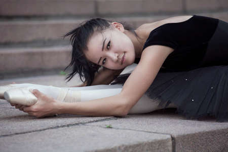 The Ballet dancer lying down and stretches on the stairsの写真素材