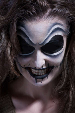 Woman with face painting in dark room (Halloween)の写真素材
