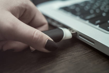 hand sticks the flash drive in the laptopの写真素材