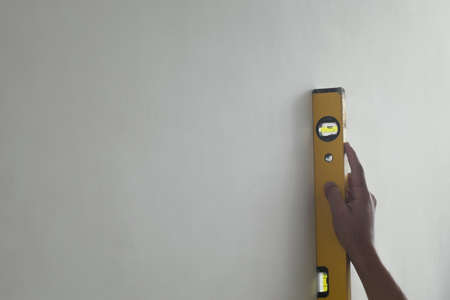 Hand holding Level against interior wall of homeの写真素材