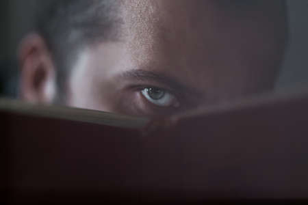 The human eye looks over booksの写真素材