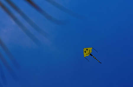 A yellow kite in a blue sky の写真素材