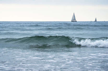 yacht with a sail and the waves of the seaの写真素材
