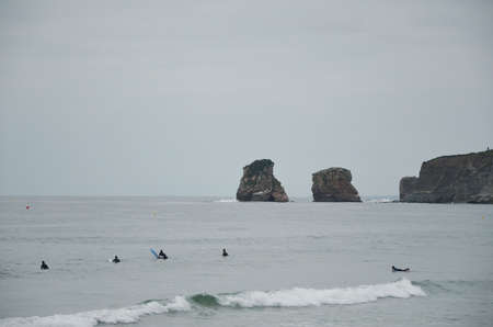 group of surfers on the waves of the ocean near the rocksの写真素材