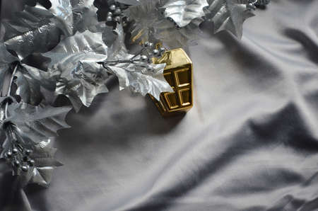 silver Christmas tree branch on a satin gray background and the Christmas Toy lantern