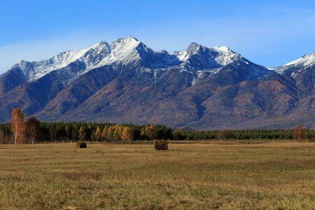 Rural landscape with haystacks in foothill valley of mountains in the background.の写真素材