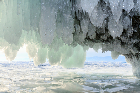 Icicles hanging from the ceiling of the stone cave and covering the entrance to the grotto Naples on lake Baikal. Photo toned.の写真素材