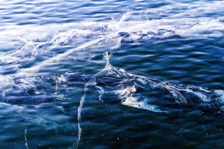 Frozen pure ice of lake Baikal with bizarre fissures reaching to the depth. Photo tinted.