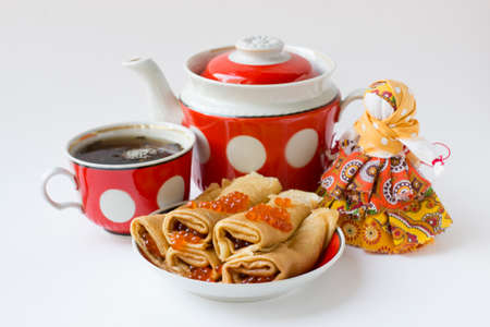 Russian pancakes with Red caviar with teapot, tea cup and textile doll isolated on white for Maslenitsa festival. Traditional Russian meal for Shrovetide.の写真素材