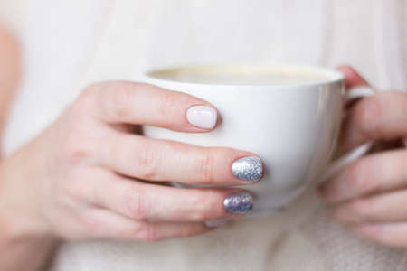 Female hands with coffee or tea cup. Woman with beautiful manicure in knitted sweater. Winter relax.の写真素材