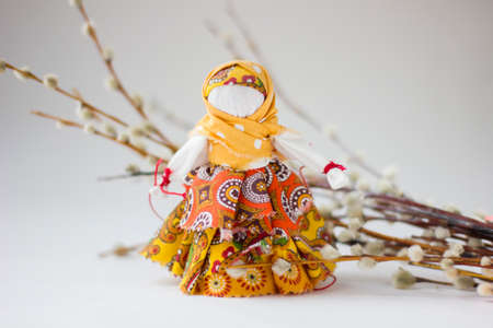 Handmade textile doll with pussy-willow on white background. Rag doll in ethnic style. Russian traditional Souvenir. Maslenitsa or Shrovetide card.の写真素材