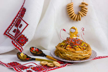 Background with pancakes, textile doll, wooden spoon, rushnik and sushki for Maslenitsa festival. Traditional Russian meal for Shrovetide. greeting card or poster.の写真素材