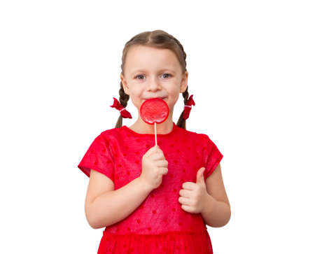 Cute happy little girl with lollipop candy in red dress isolated on white background.の写真素材
