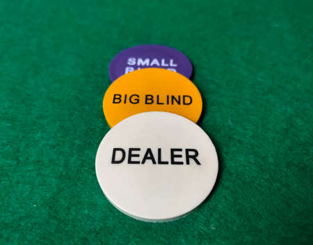 Chips dealer, big blind and small blind on the table on the green baize.