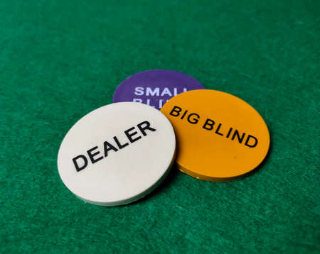 Chips dealer, big blind and small blind on the table on the green baize.