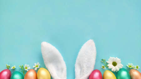 Easter background with Easter eggs, bunny ears and flowers. Top view with copy space.