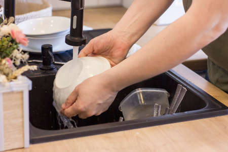 Closeup of mans hands washing dishes in kitchen sink. cleaning chores. home routine.