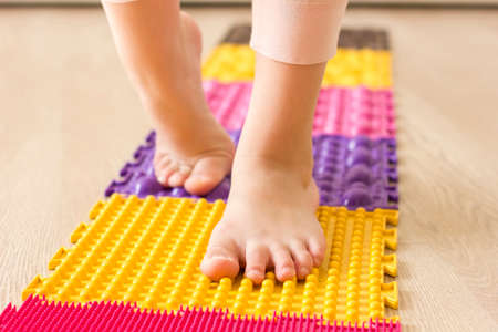 Closeup little girls feet on orthopedic massage mat. Foot massage for child.の写真素材