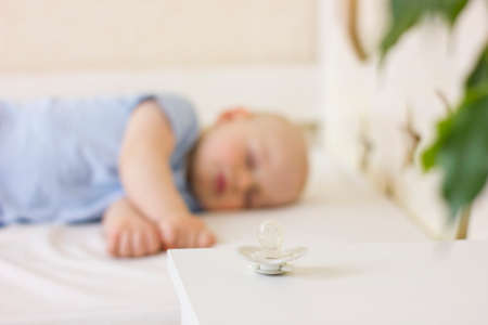 Cute baby boy toddler sitting on the floor at home and collects a pyramid toy. Development of fine...