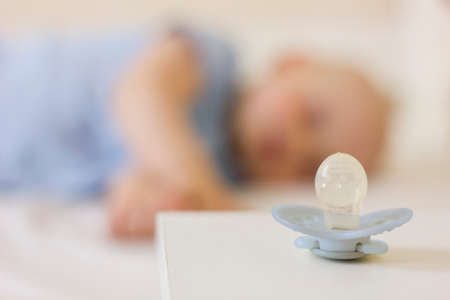 Cute baby boy toddler sitting on the floor at home and collects a pyramid toy. Development of fine...