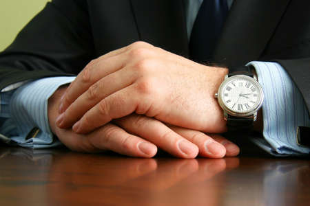 Hands of businessman in suit and shirt with cufflinks and with the clock