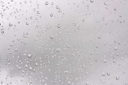 Water drops on glass against the storm sky