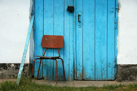 Single chair in front of old doorの写真素材