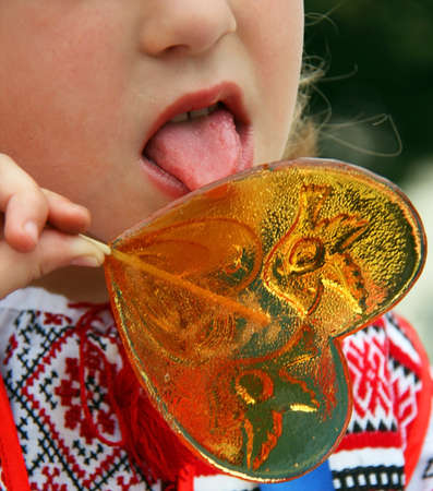 Little girl holding a big heart shaped lollipop