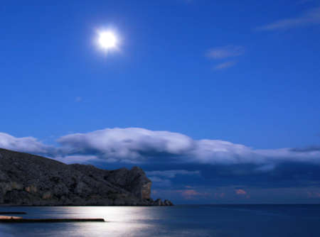 Evening landscape of the sea and the mountain range of the moon in the skyの写真素材
