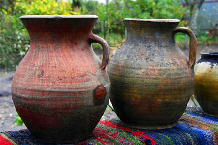 Old Ukrainian clay jugs stand on a table in the gardenの写真素材