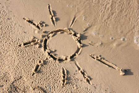 Drawn on the sand of the sun, which washes off a waveの写真素材