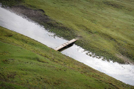 Narrow old wooden bridge through a river
