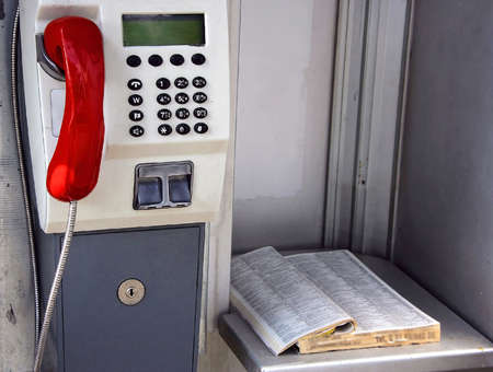 Payphone and an old telephone directory in call boxの写真素材