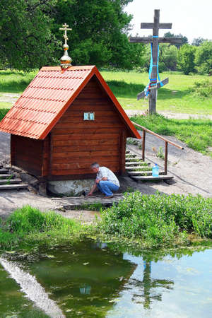 A man takes water from the source of healing near the Ukrainian village のeditorial素材