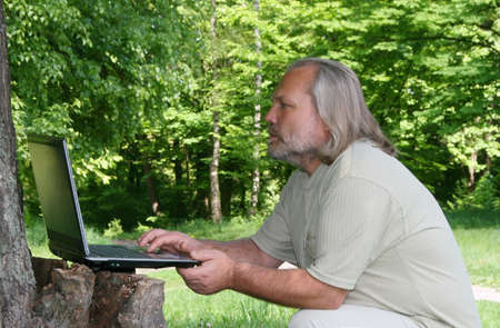 Man with a laptop sitting under the treeの写真素材