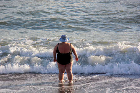 Woman with overweight in hat on a background of the seaの写真素材