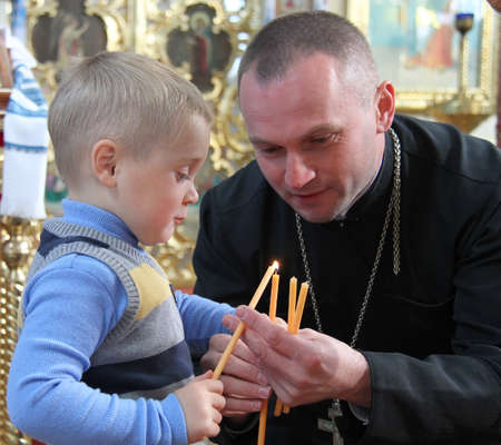 LUTSK, UKRAINE - OCTOBER 28 - Orthodox priest and the boy lit a candle in Lutsk on October 28, 2014.のeditorial素材