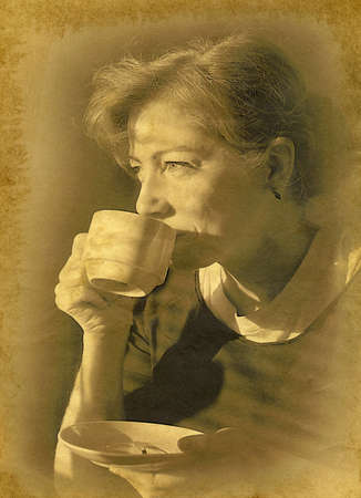 Woman holding a cup of coffee in the morning. Vintage effect of the old paper.