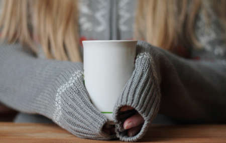 Hands holding mug of hot drink. Shallow depth of field.