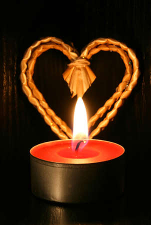 Closeup of burning candle and heart on black backgroundの写真素材